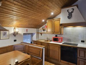 a kitchen with wooden cabinets and a table and a microwave at San Rocco Lodge in Livigno