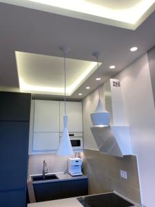 Una cocina con tres luces colgando del techo. en Apartman V, en Belgrado