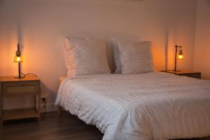 Un dormitorio con una cama blanca con dos lámparas sobre mesas. en Escale Atlantique, en Saint-Nazaire