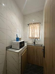 Una pequeña cocina con microondas y fregadero. en Maxwells Inn Yaba, en Lagos