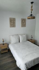 Un dormitorio con una cama blanca con dos mesitas de noche. en Escale Atlantique, en Saint-Nazaire