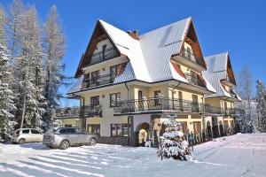 a house in the snow with cars parked in front at Dom Wypoczynkowy Podhalanka in Białka Tatrzańska