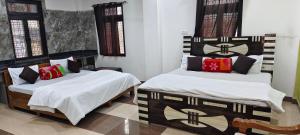 a bedroom with two beds with white sheets and colorful pillows at Dev Guest House in Aklera