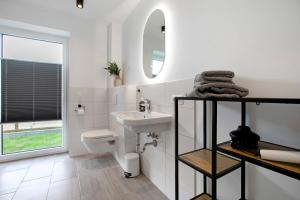 a white bathroom with a sink and a toilet at Ferienhaus Ebbe in Schülp +24 photos