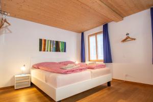 a bedroom with a bed with blue curtains and a window at Studio Zentrum EG in Adelboden