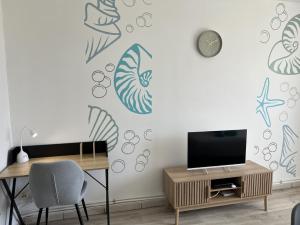 een woonkamer met een tv en een tafel en een klok bij Soleiade Le Gosier - Accès Plage in Le Gosier