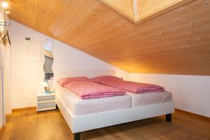 ein Bett in einem Zimmer mit Holzdecke in der Unterkunft Studio Zentrum OG in Adelboden