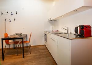 eine Küche mit einem Tisch, einer Spüle und einer Theke in der Unterkunft Studio Zentrum OG in Adelboden