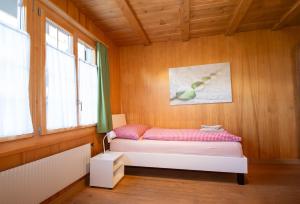 Bett in einem Zimmer mit Holzwänden und Fenstern in der Unterkunft Im Zentrum in Adelboden