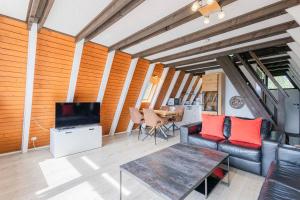 ein Wohnzimmer mit einer Couch, einem Fernseher und einem Tisch in der Unterkunft Ferienwohnpark Immenstaad am Bodensee Nurdachhaus Typ 7 ND 15 in Immenstaad am Bodensee