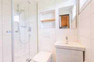 ein weißes Badezimmer mit Toilette und Dusche in der Unterkunft Ferienwohnpark Immenstaad am Bodensee Nurdachhaus Typ 7 ND 15 in Immenstaad am Bodensee + 15 Fotos