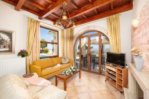 a living room with a yellow couch and a tv at Teacher Cottage in Agia Triada