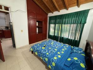 a bedroom with a bed with a blue comforter and a window at Apartamento barrio Simón Bolívar in Roldanillo