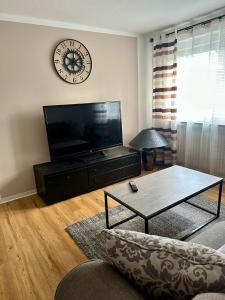 a living room with a tv and a clock on the wall at Ferienwohnung am Bürgerpark in Verden