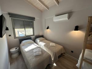 Olive Grove Villas Galaxidi في غالاكسيدي: غرفة صغيرة بها سريرين ونافذة