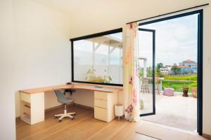 ein Büro mit Schreibtisch und großem Fenster in der Unterkunft Senyum Villa in Canggu