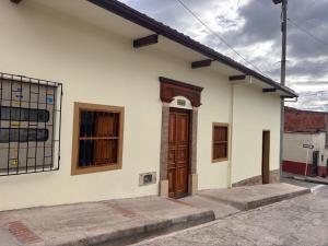 a white building with a wooden door and windows at Hostal Boutique Loto de Belén in Bogotá