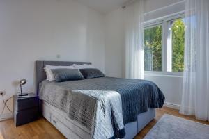 a white bedroom with a bed and a window at Aparatman Residence in Rijeka