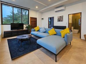 un salon avec un canapé bleu et une télévision dans l'établissement v15 Ocean Serenity Residence, à Ko Pha Ngan