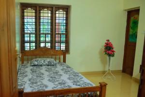 - une chambre avec un lit et un vase de fleurs dans l'établissement Home Near Sabarimala, à Rānī