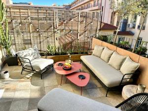 a patio with a couch and chairs and a table at L'âme de Nice - Terrasse dorée sur Place Masséna in Nice
