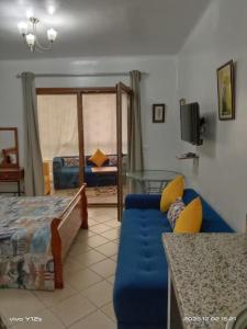 Una sala de estar con un sofá azul y una cama. en studio avec piscine et wifi à cabonegro, en Cabo Negro 24 fotos más