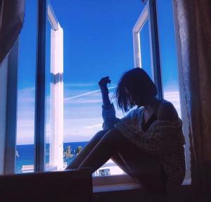 a woman sitting in front of a window at Khách Sạn - Homestay QUANG VINH Đảo Lý Sơn in Ly Son