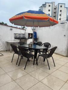 a table and chairs with an umbrella on a patio at Condomínio Martim de Sá in Caraguatatuba