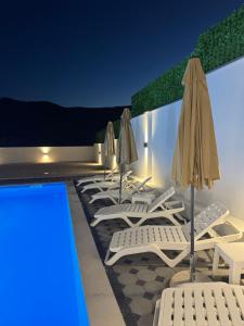 a row of lounge chairs and umbrellas next to a pool at Hubby Resort in Mostar