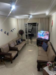a living room with couches and a flat screen tv at Condomínio Martim de Sá in Caraguatatuba +5 photos