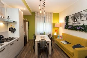 eine Küche und ein Wohnzimmer mit einem gelben Sofa und einem Tisch in der Unterkunft Segui le note della Tua vita in Cremona