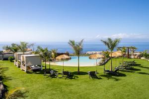 una vista di un prato con sedie e una piscina di Experiencia Habitación Burbuja con Jacuzzi Privado, Piscina y Vistas al Mar a Guía de Isora