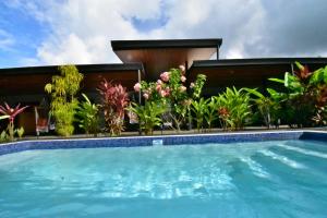 a swimming pool in front of a house with plants at Raya in Matapalo