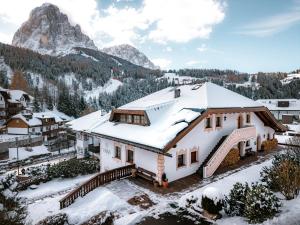 a house covered in snow with a mountain in the background at Anna Lodges Dolomites in Santa Cristina in Val Gardena
