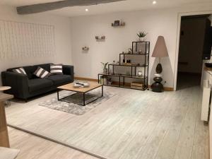 a living room with a black couch and a table at La petite maison normande in Luneray