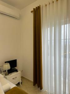 ein Schlafzimmer mit einem Bett und einem Fenster mit Vorhängen in der Unterkunft Vila Dy Bukurite in Draç