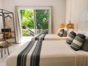 two beds in a room with a window at Hotel Aires Bacalar in Bacalar