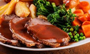 a plate of food with meat and vegetables on a table at The White Hart Hotel in Shefford