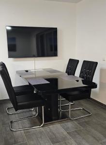 a black table with four black chairs and a flat screen tv at MY HOME 23 Nr 8 in Villingen-Schwenningen