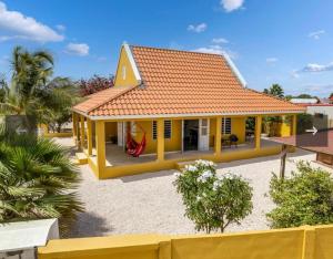 a small yellow house with a red roof at villa suiker tuintje in Kralendijk