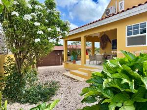 a backyard with a yellow house with a patio at villa suiker tuintje in Kralendijk +12 photos
