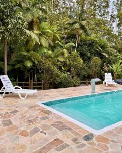ein Swimmingpool mit zwei weißen Stühlen neben einem Resort in der Unterkunft Sítio Feltz in Canelinha