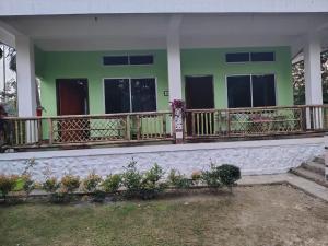 Casa verde y blanca con balcón en Deer Dee Home Stay, en Jyoti Gaon