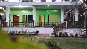 una casa con un verde y blanco en Deer Dee Home Stay, en Jyoti Gaon