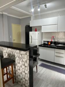a kitchen with white cabinets and a black counter top at Apartamento canto do forte in Praia Grande +3 photos
