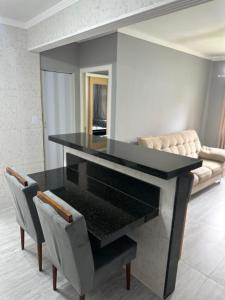 a dining room with a black table and a couch at Apartamento canto do forte in Praia Grande
