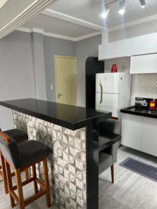 a kitchen with a black counter and a refrigerator at Apartamento canto do forte in Praia Grande