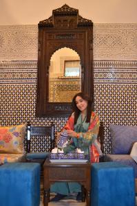 una mujer sentada en una mesa en una habitación en Riad Dar Salma, en Fez