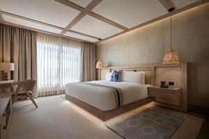 ein Schlafzimmer mit Bett, Schreibtisch und Fenster in der Unterkunft Hotel Indigo Playa del Carmen by IHG in Playa del Carmen