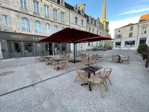 Hôtel Le Riche'Lieu في لوكون: فناء مع طاولات وكراسي ومظلة